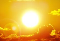 The sun shining brightly in a golden sky with clouds