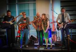 Band performing live on stage with guitars, drums and vocalists