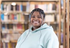 Colleague in a library setting stood in front of a bookshelf