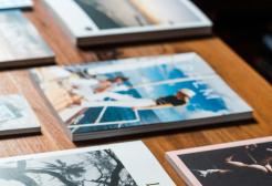 Several printed magazines and brochures arranged on a wooden table, displaying a variety of cover designs, photographs, and typography