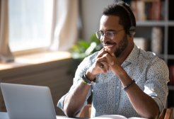 A person wearing headphones while working on a laptop