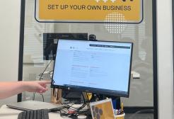 A student sat opposite a help desk looking at a computer 
