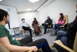 Six students engaged in a discussion while seated in a circle within the Counselling Suite.