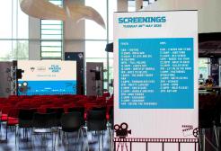 Rows of chairs set up for the Film Production Awards, with a large banner listing the screening schedule. 