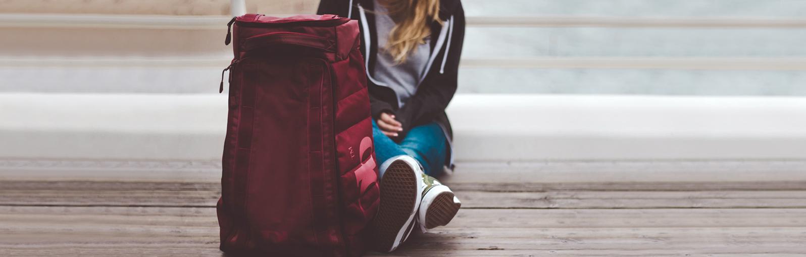 Woman sat with a red rucksack on a wooden floor