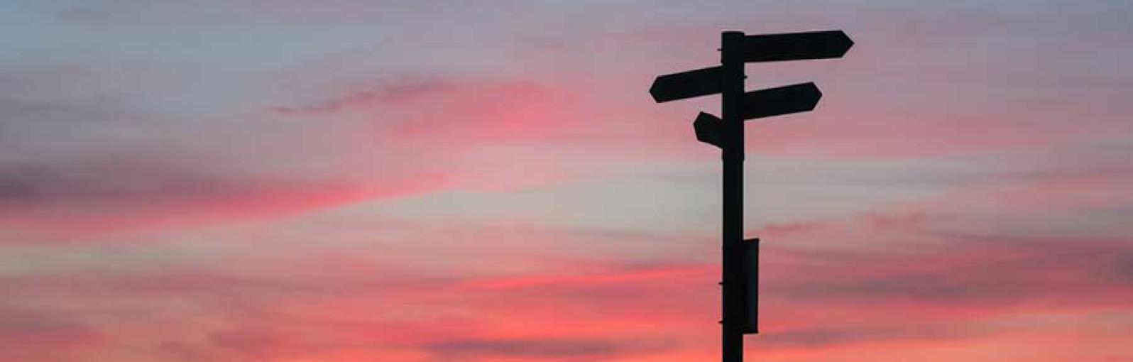 A signpost with a blue and pink sky behind it