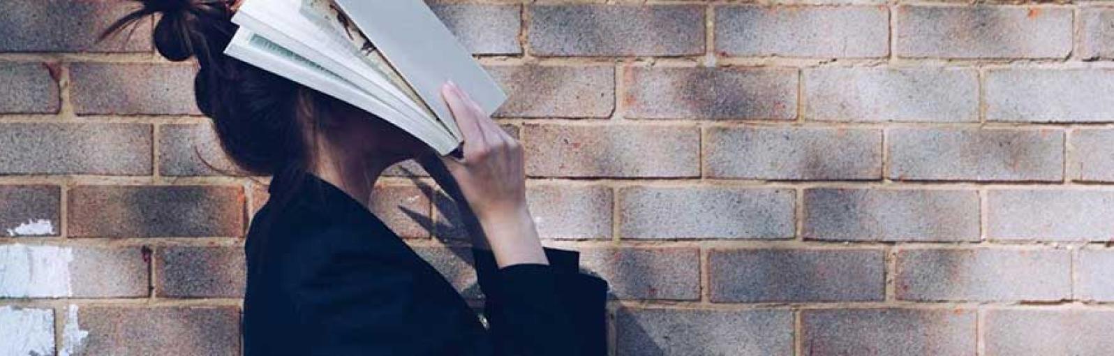 A person holds a book over their face