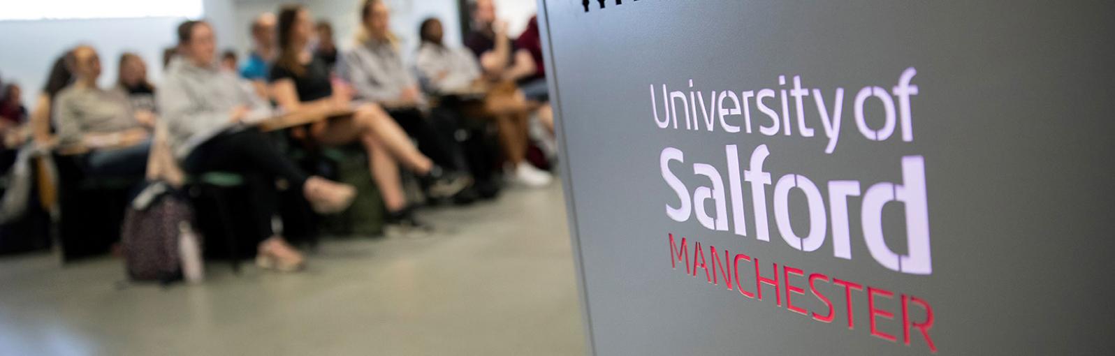 University of Salford lecture podium with students in the background