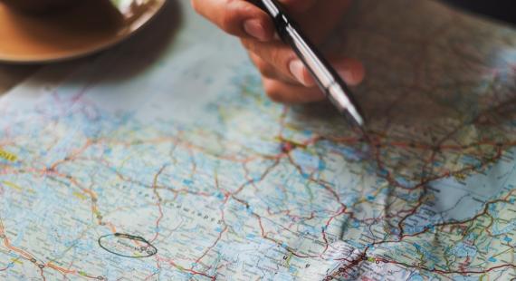 Person holding a pen and making notes on a world map