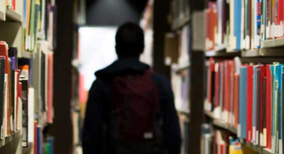 A person stands between shelves in a library