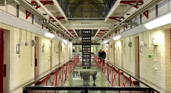 Photograph of the inside of a prison with people walking around. 