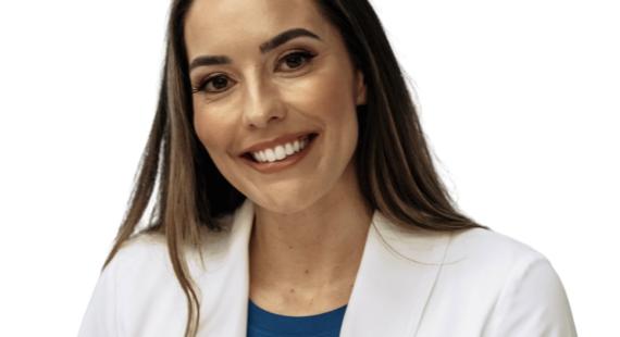 University Fellow Ashley Gluchowski smiling wearing a white jacket and blue top