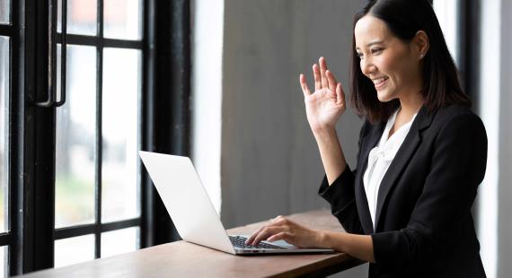 woman waving at colleagues on work laptop