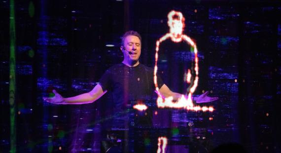 A man performs next to a holographic figure