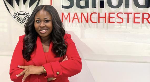 Maudlyn Akosua Awuku in front of the University of Salford logo
