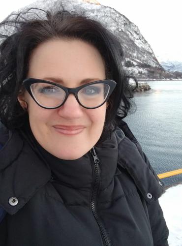 Inez taking a selfie in Volda, with a frozen mountain and the sea in the background