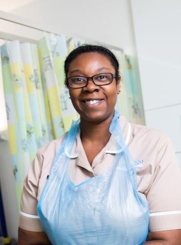 Nursing associate apprentice putting on gloves in a simulated ward environment