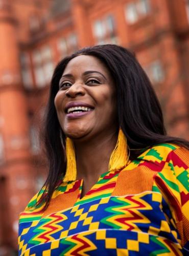 Alumni volunteer smiling outside Peel Building, University of Salford