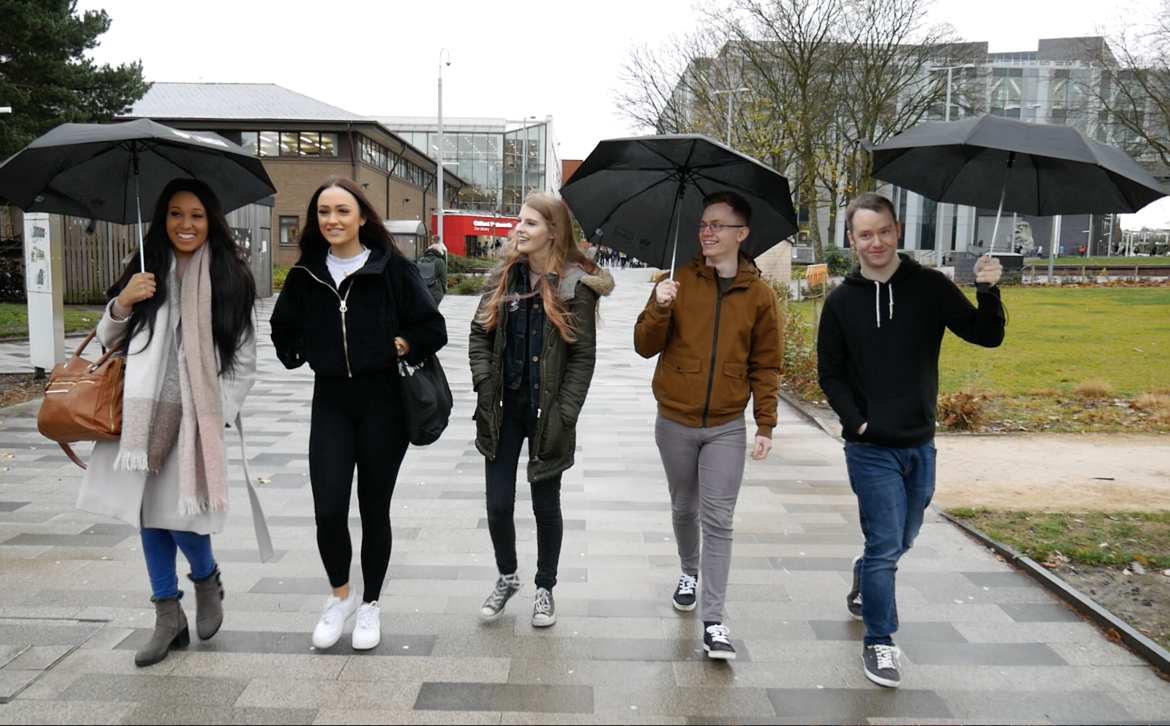 Group of students with umbrellas walking down the broadwalk on a rainy day