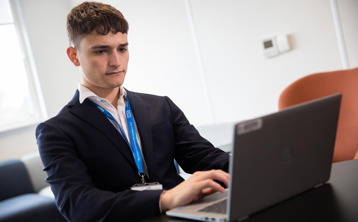 Harry Rosenberg using a laptop on placement with the NHS