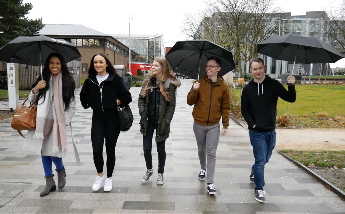 Group of students with umbrellas walking down the broadwalk on a rainy 