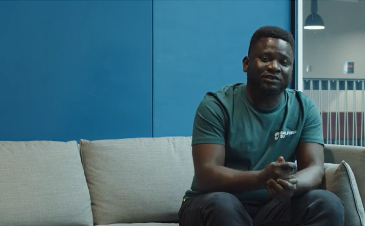 Student Akinwale Belo sittiting on a couch