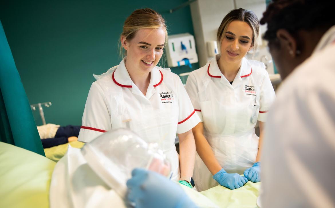 Three nursing students practicing on a model of a child