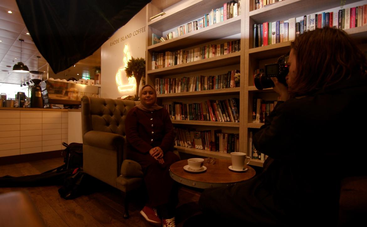 A photographer taking a photograph of Amina Lorgat in a cafe