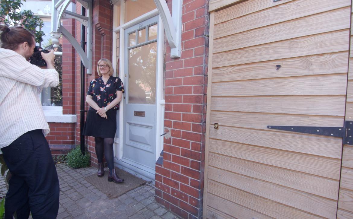 A photographer taking a photograph of Anna Webster outside her home