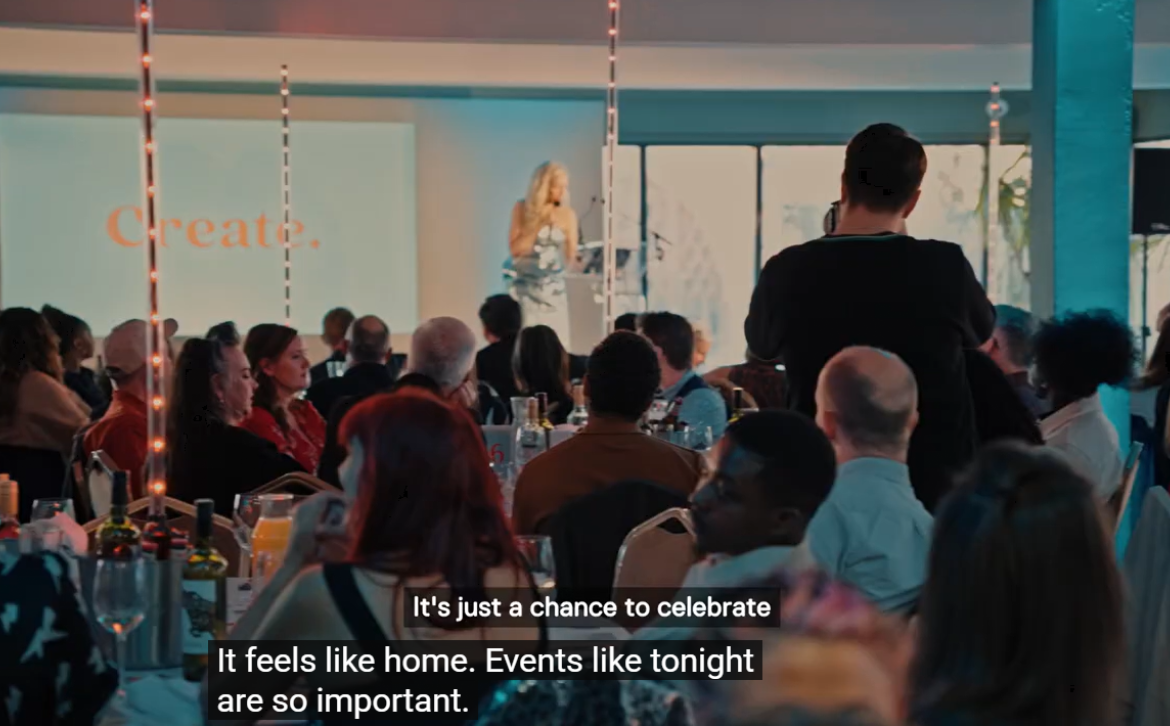 A photo of someone on stage at the 2026 Create Awards with the audience seated and listening to them